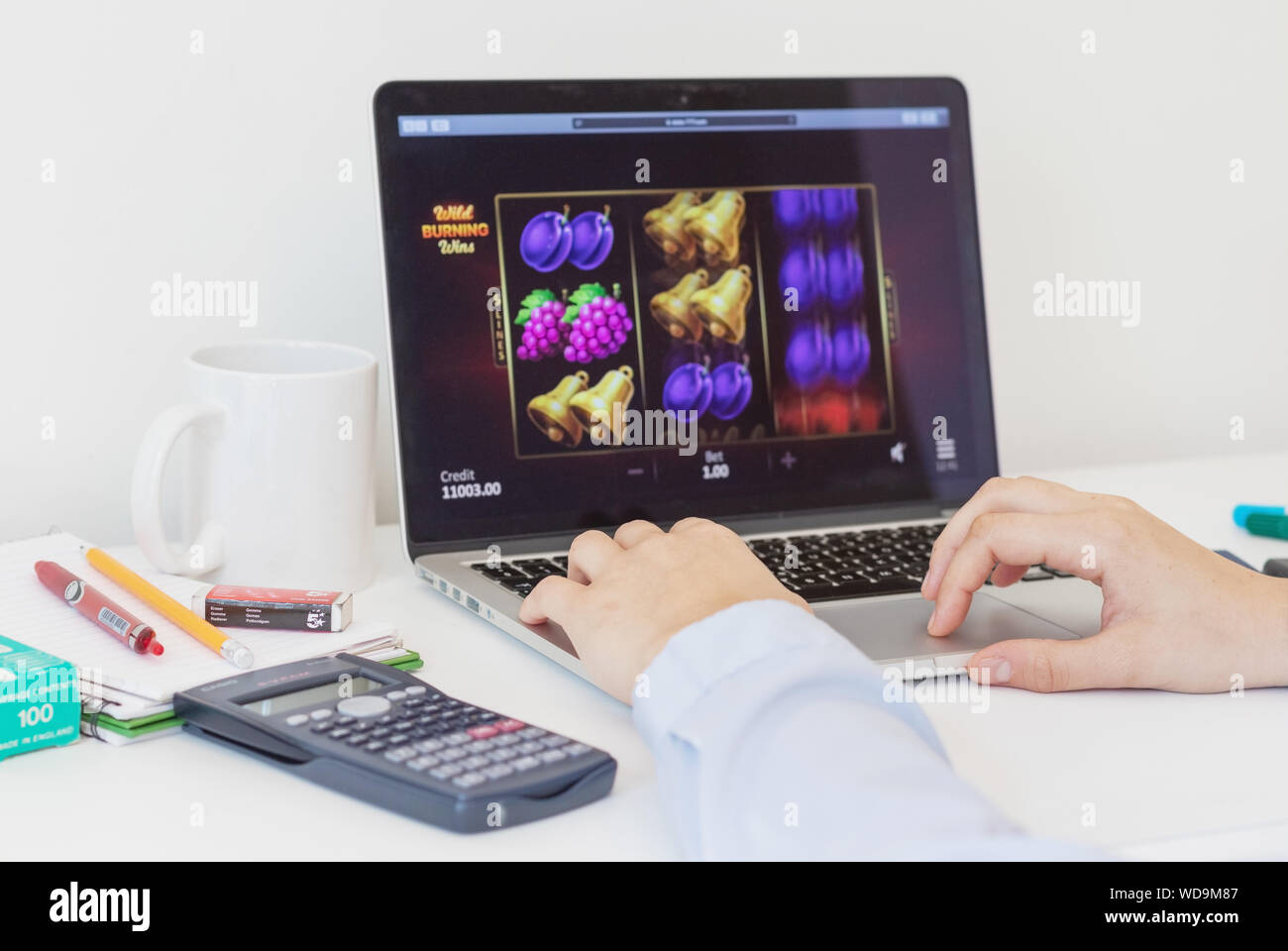 London / UK, 24 agosto 2019 - Dipendente online gambling sul lavoro, giocando un frutto slot machine su un computer portatile. Primo piano con una profondità di f Foto Stock