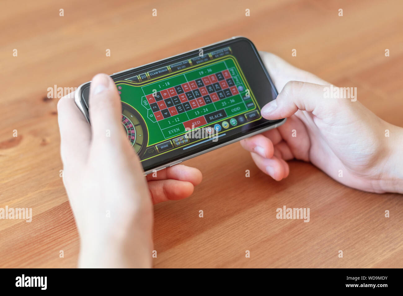 London / UK, 24 agosto 2019 - Primo piano delle mani il gioco d'azzardo sul telefono mobile device, con una profondità di campo ridotta. Foto Stock