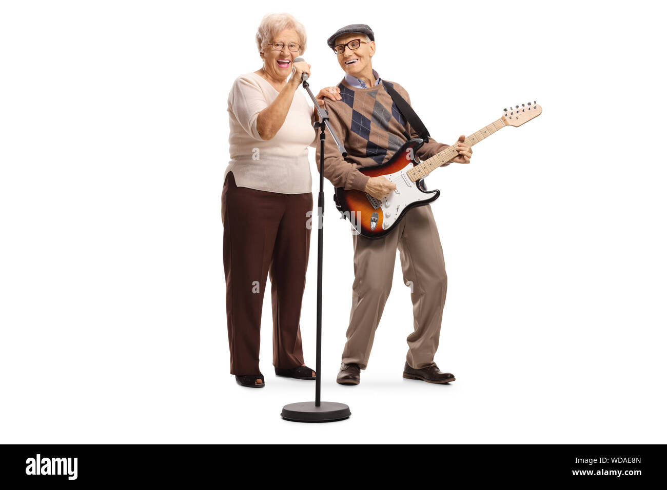 A piena lunghezza Ritratto di una donna anziana cantando su un microfono e un anziano gentiluomo di suonare una chitarra isolato su sfondo bianco Foto Stock