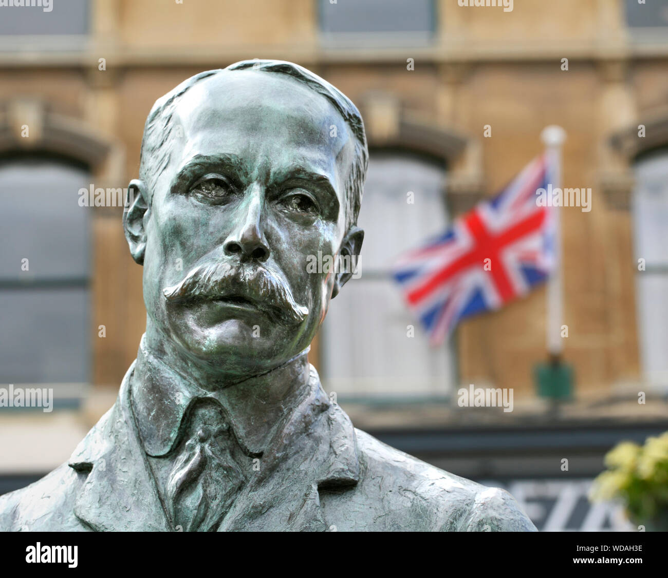 Una statua di Edward Elgar nel centro di Great Malvern, Worcestershire, con una bandiera inglese battenti in background. Foto Stock