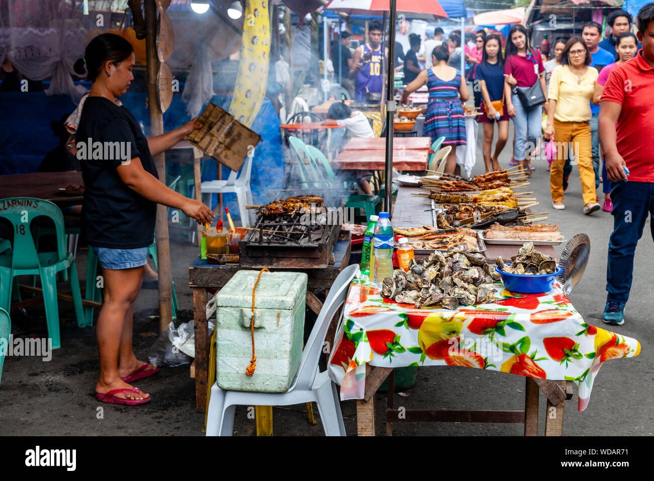 Filippino cibo di strada, una donna filippina la cottura della carne su un grill, Iloilo City, Panay Island, Filippine Foto Stock
