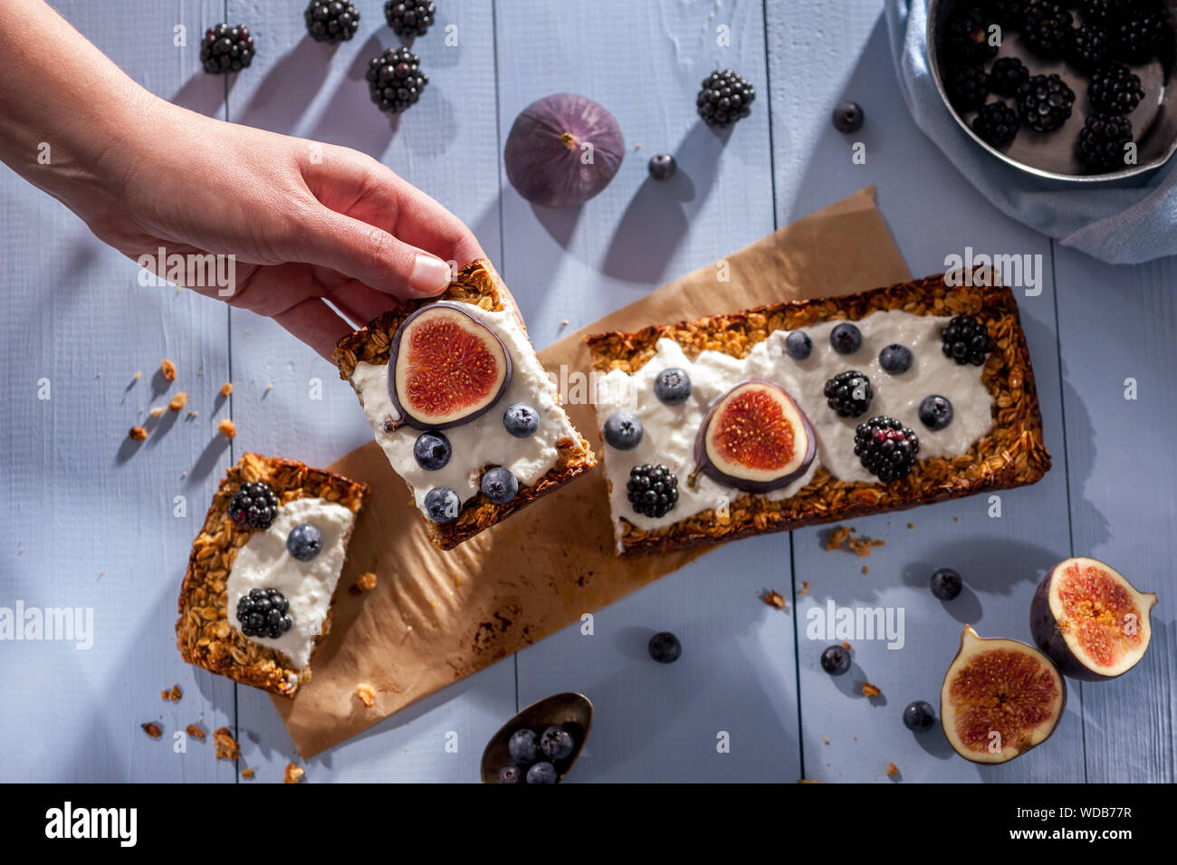 Raccolta a mano pezzo di torta di fiocchi d'avena con yogurt naturale, miele, fichi freschi, more e mirtilli Foto Stock