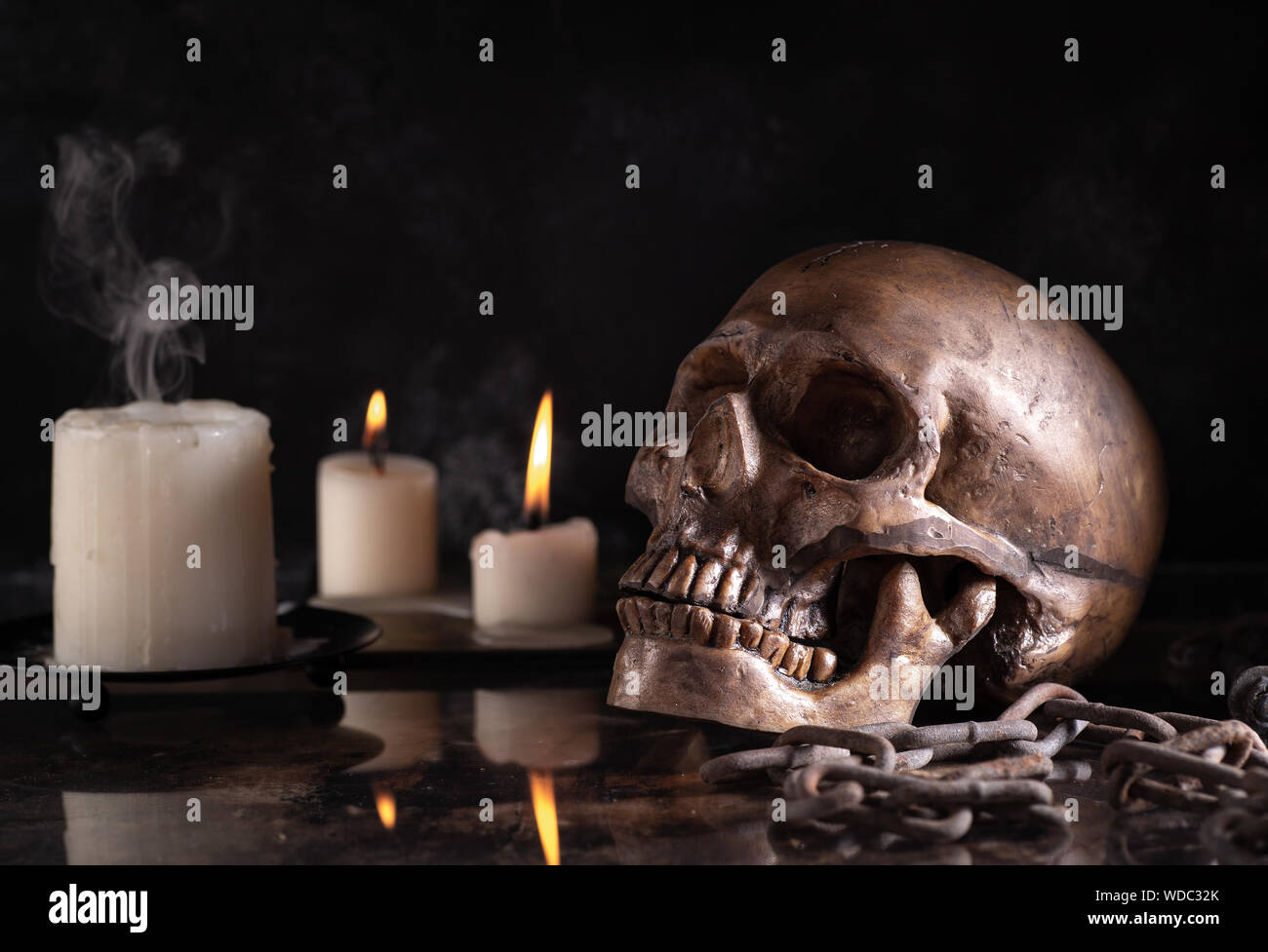 Scary teschio umano con candele su uno sfondo nero. Concetto di Halloween Foto Stock