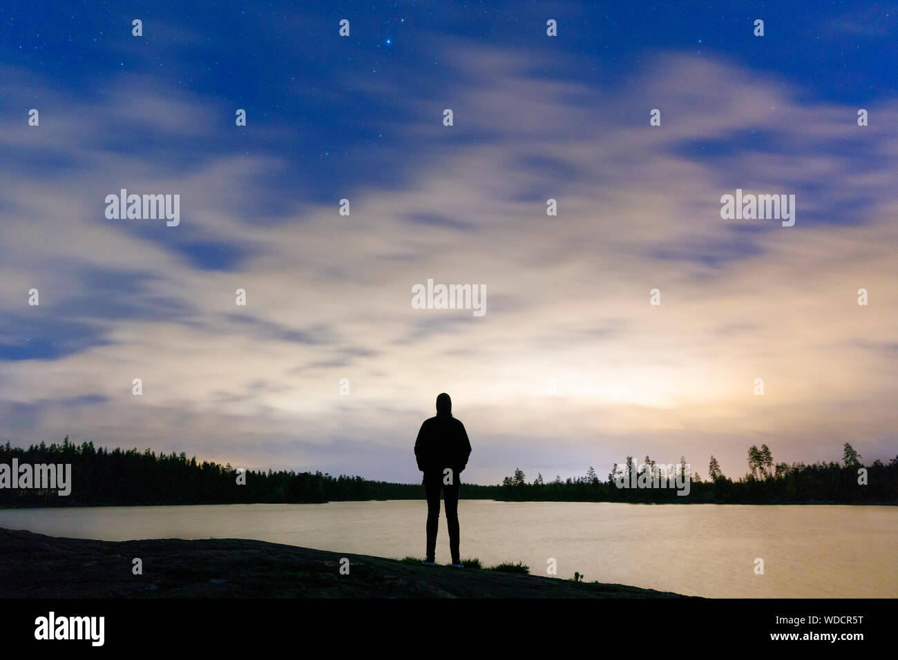 Silhouette di donna in piedi dal lago al tramonto Foto Stock