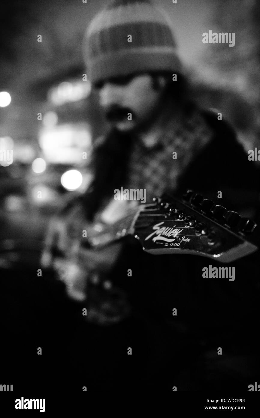 Bianco e nero street photography di una strada chitarrista. Egli svolge la sua chitarra elettrica anche a notti fredde dell'inverno. Foto Stock