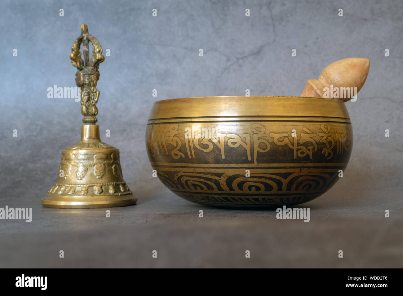 Singing Bowl e golden bell close-up, calmante e meditativa. Singing Bowl con incisione sanscrito pattern e un mazzuolo di legno e campana dorata di su g Foto Stock