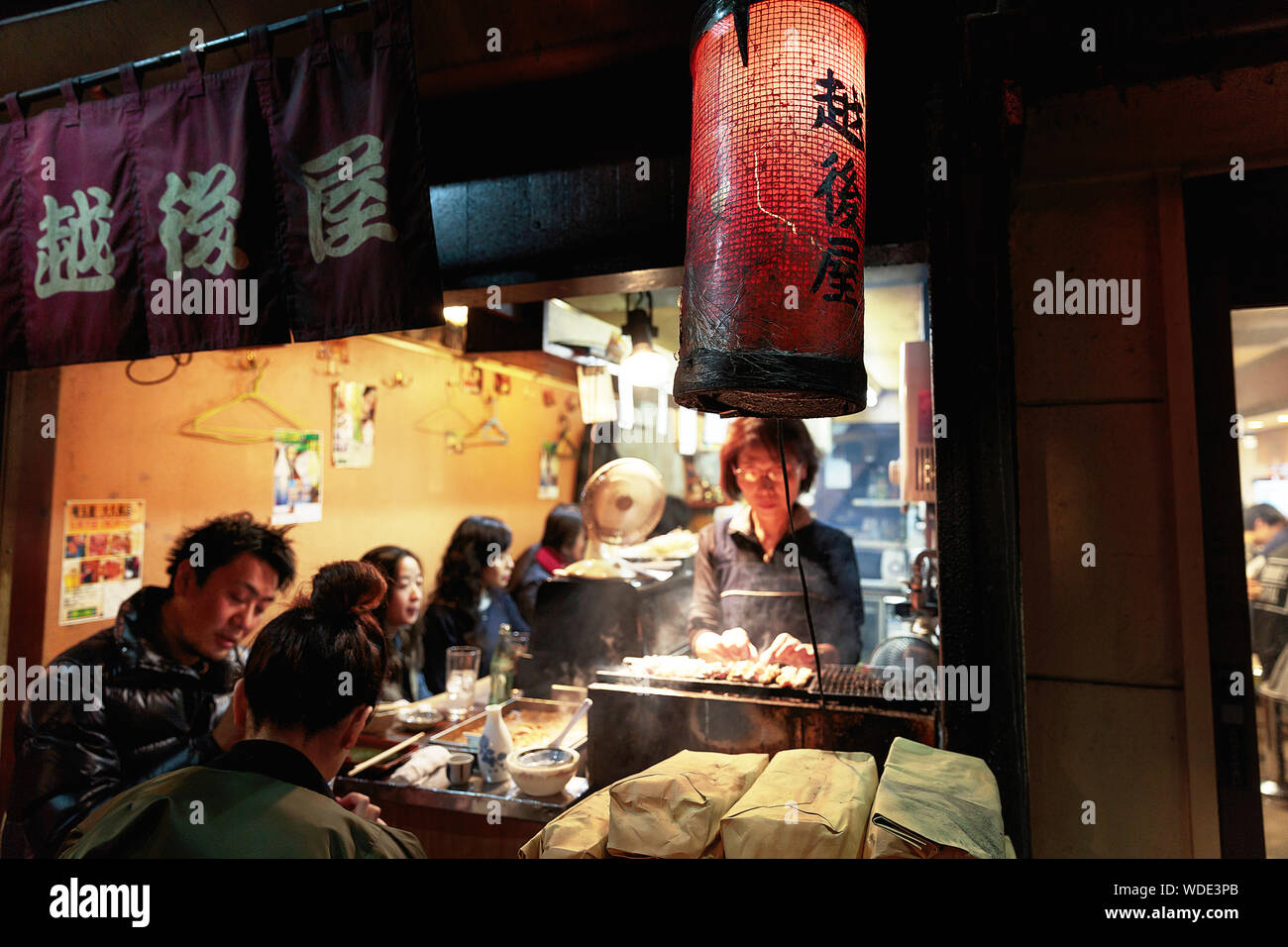 Le persone godono di bevande e cibo di strada all'interno di un piccolo pub in Omoide Yokocho vicolo. Foto Stock