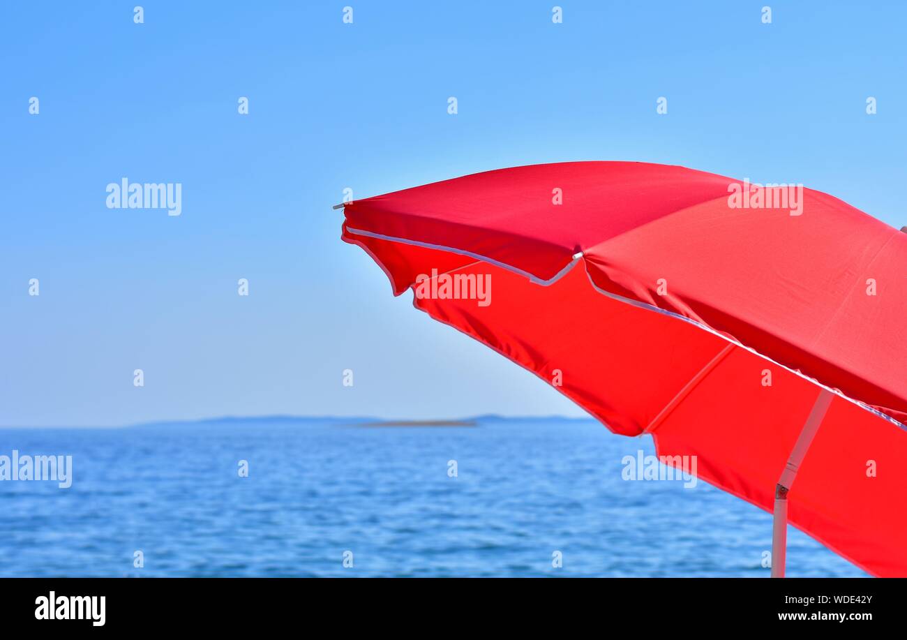 Dettaglio del parasole rosso con il mare e il cielo in background su un estate calda giornata Foto Stock