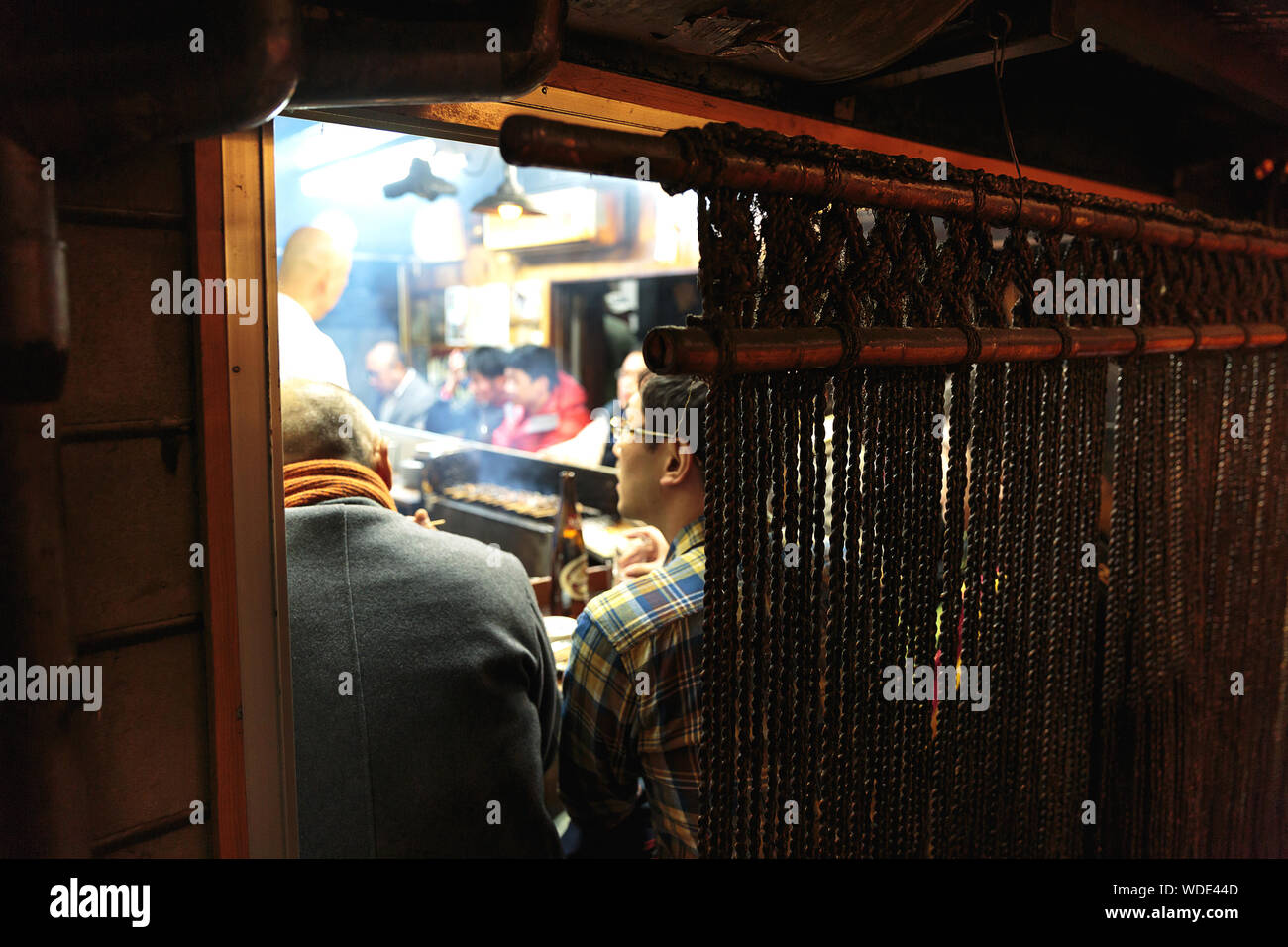 Le persone godono di bevande e cibo di strada all'interno di un piccolo pub in Omoide Yokocho vicolo. Foto Stock