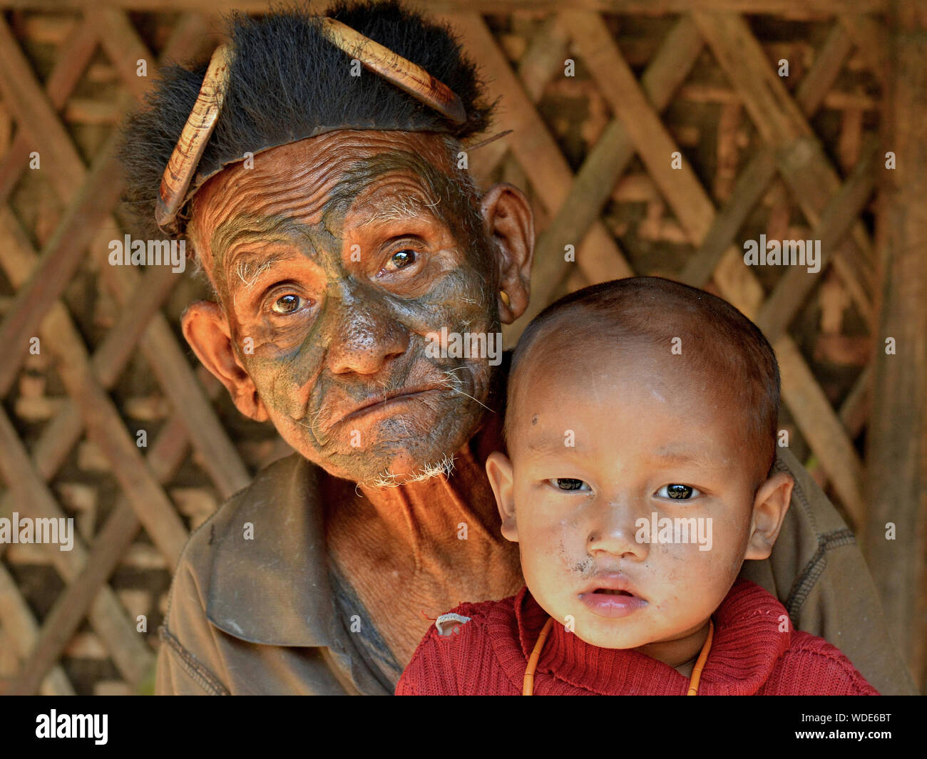 Vecchio, pensionato Konyak indiano Naga guerriero e ex-headhunter e il suo piccolo grande nipote pongono per la fotocamera. Foto Stock