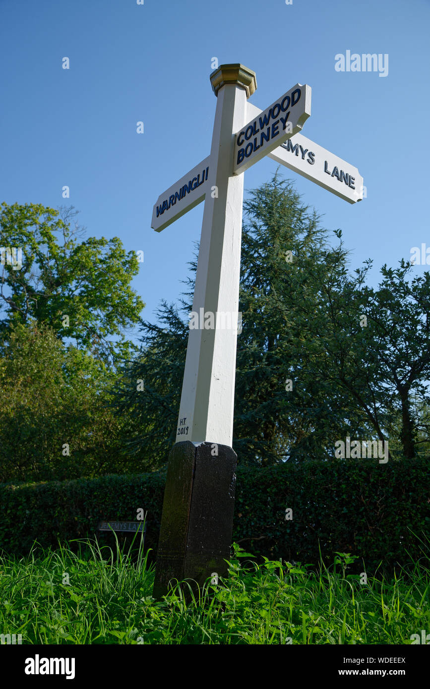 Un fingerpost di legno o segnaletica nel West Sussex, Regno Unito. Bianco e nero rovere verniciato post direzionale. Foto Stock