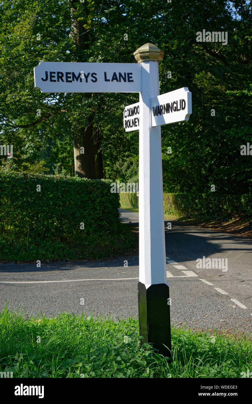 Un fingerpost di legno o segnaletica nel West Sussex, Regno Unito. Bianco e nero rovere verniciato post direzionale. Foto Stock