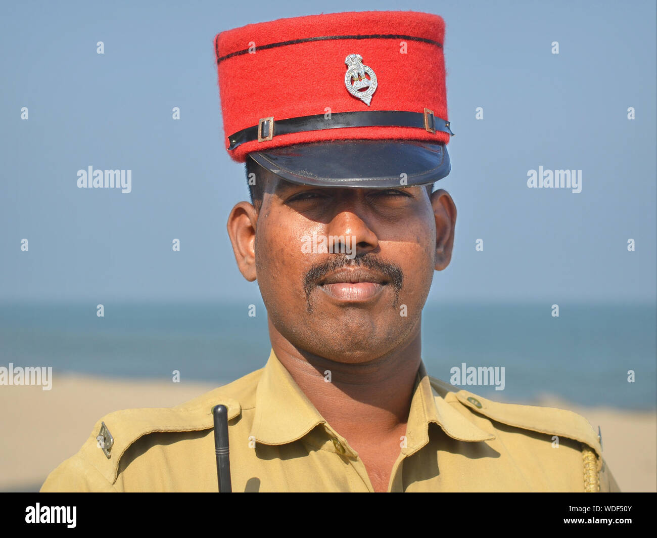 Giovani indiani Puducherry poliziotto indossa una polizia Red Hat e pone per la fotocamera. Foto Stock
