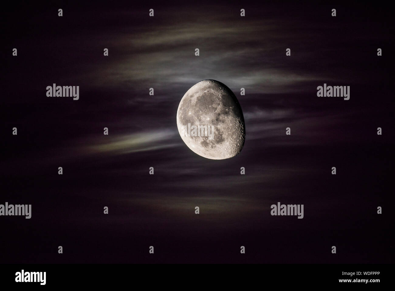 Immagine composita della luna contro un cielo con striata nuvole e una tonalità di viola. Foto Stock