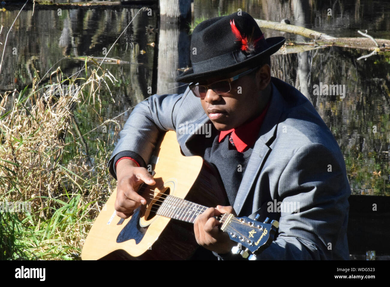 Uomo vestito da indossare a suonare la chitarra mentre è seduto in cantiere  Foto stock - Alamy