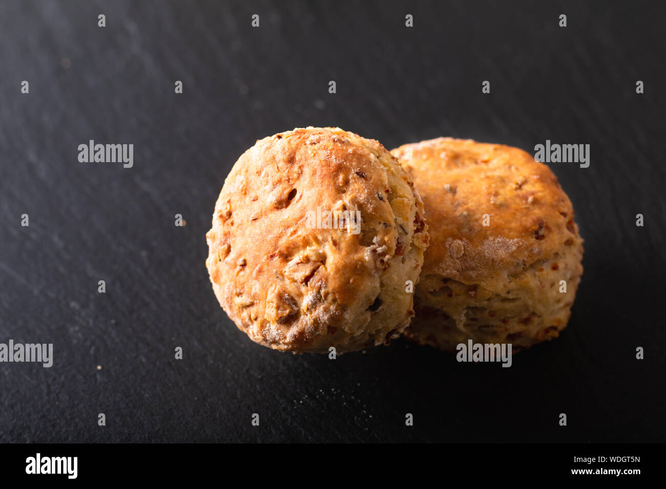 Concetto di alimenti freschi di forno in casa burrosa, salato prosciutto e formaggio scones su sfondo nero Foto Stock