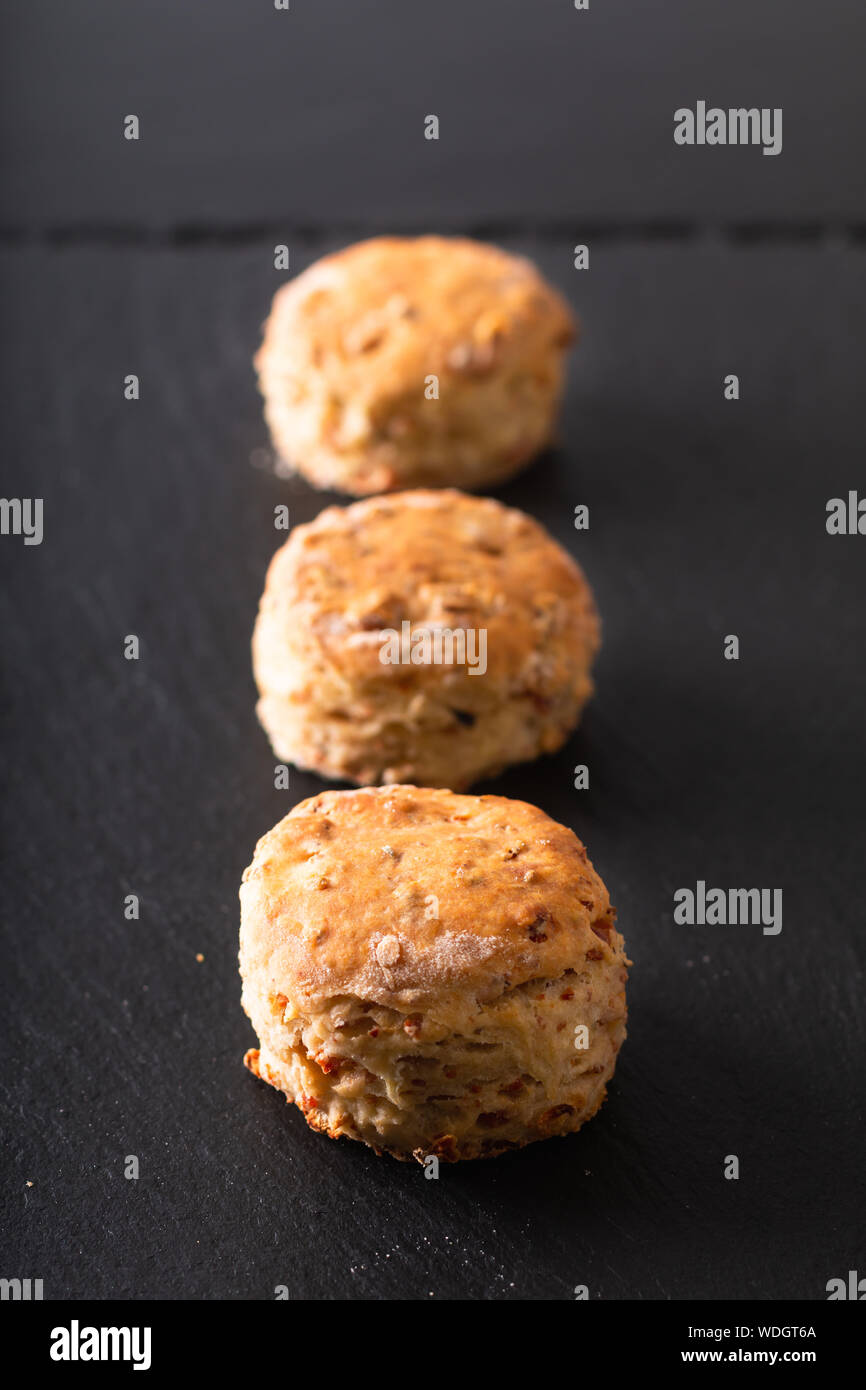 Concetto di alimenti freschi di forno in casa burrosa, salato prosciutto e formaggio scones su sfondo nero Foto Stock