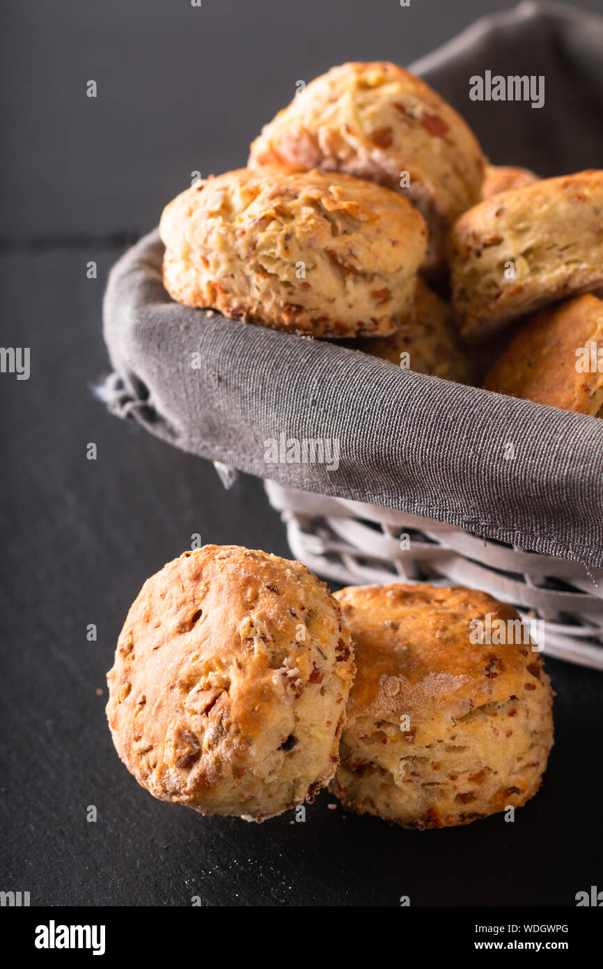 Concetto di alimenti freschi di forno in casa burrosa, salato prosciutto e formaggio scones su sfondo nero Foto Stock