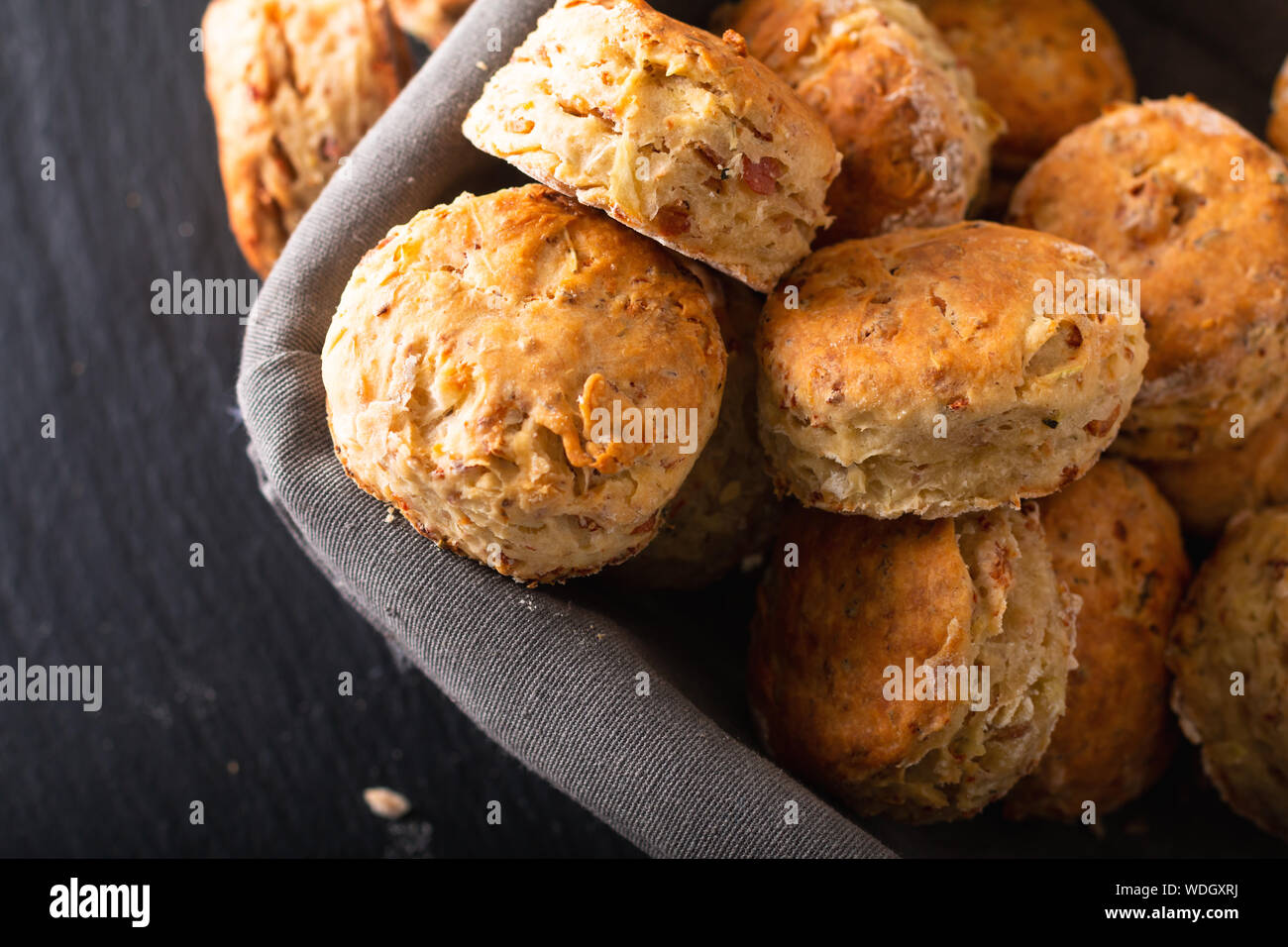 Concetto di alimenti freschi di forno in casa burrosa, salato prosciutto e formaggio scones su sfondo nero Foto Stock