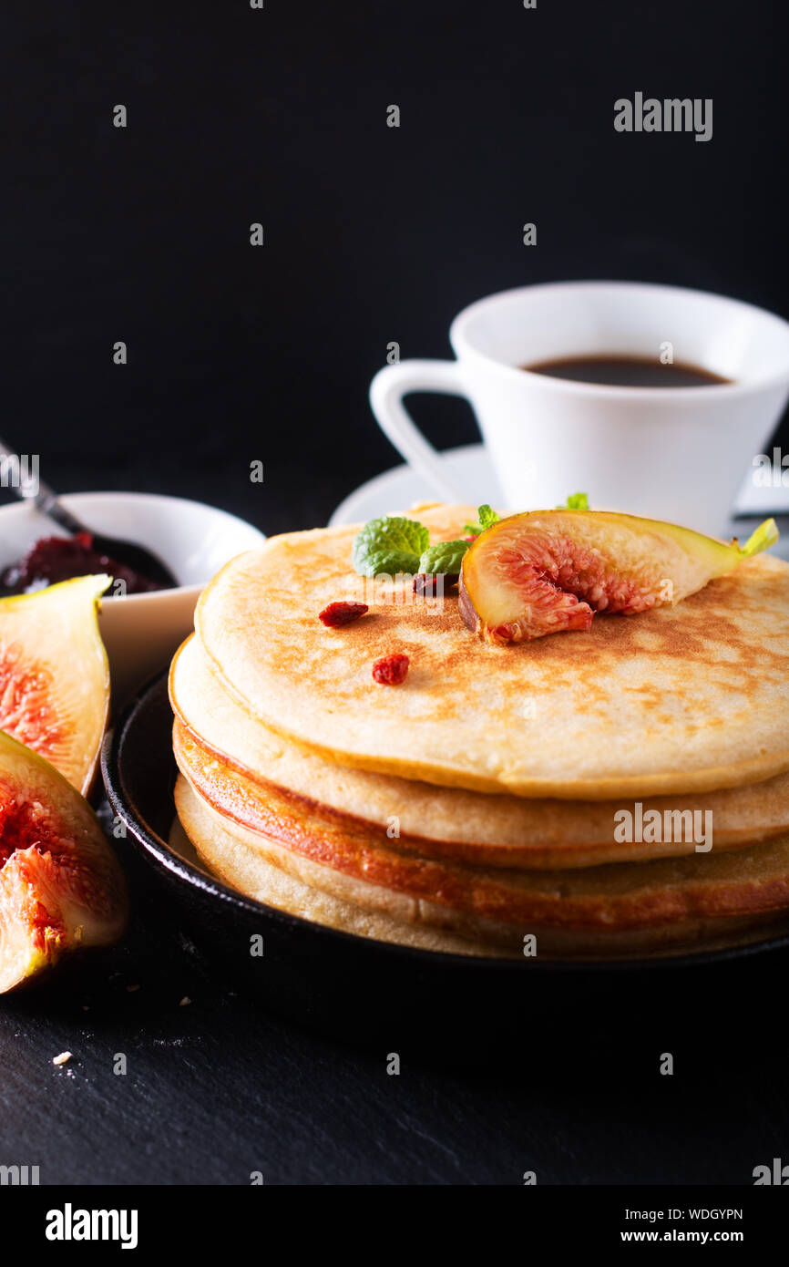 Concetto di cibo in casa frittelle organico stack con fig colazione su sfondo nero Foto Stock