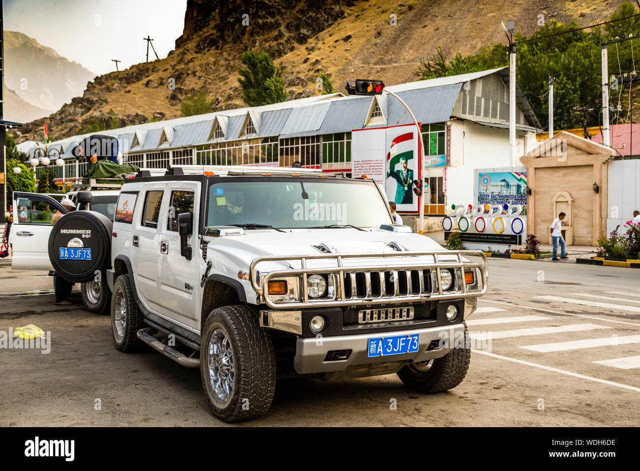Auto cinese ufficiale a Convoy sulla Via della Seta a Qalai Khumb, Tagikistan. Sullo sfondo: Monumento per ricordare l'attacco fatale ai ciclisti nel 2018 Foto Stock