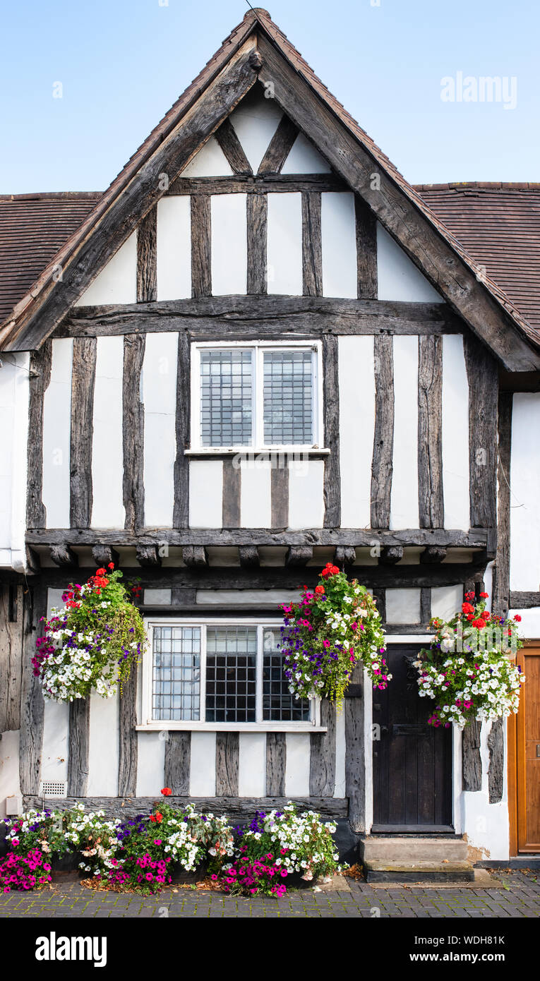 Tudor la struttura di legno bianco e nero casa medioevale con motivi floreali nei cestini appesi. Warwick Warwickshire, Inghilterra Foto Stock