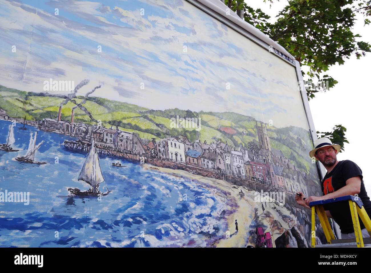 Artista britannico David Downes è stata commissionata da ITV per creare un grande murale pubblica in Bournemouth in concomitanza con il lancio del loro dramma 2019 Sanditon in agosto 2019. Pittura pubblicamente per 5 giorni, e qui il giorno 5, Downes è ricreare una versione illustrata del poster artwork per Sanditon, su un enorme cartellone nel Regno Unito la città costiera, per riflettere la posizione sul mare del dramma. L'installazione rimarrà in situ per tre settimane dopo il suo completamento. David Downes è un pittore paesaggista che amplifica il senso di luogo e di tempo attraverso la lente di autismo. Foto Stock