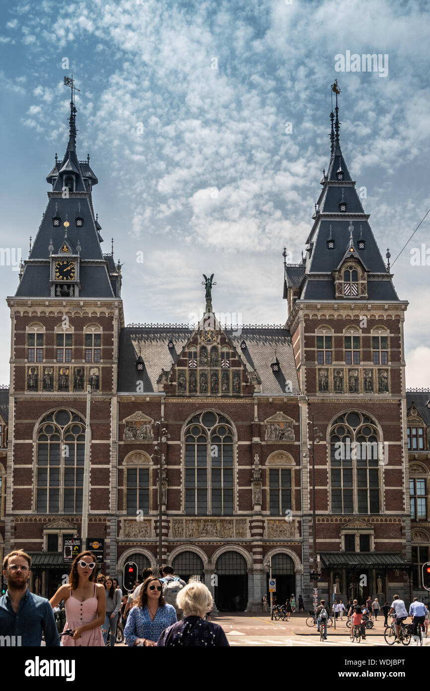 Amsterdam, Paesi Bassi - 30 Giugno 2019: ingresso monumentale facciata con torri in beige e mattoni rossi. Statue e affreschi. In blue-whtie clo Foto Stock