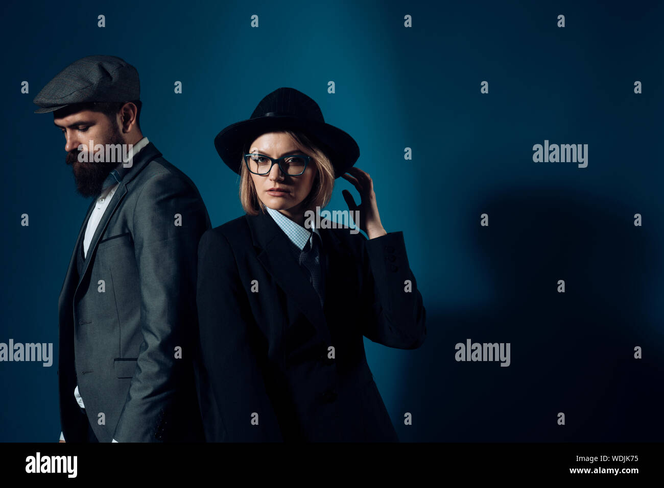 L uomo e la donna in oldfashioned tuta e hat su sfondo scuro. Coppia di detective o ricercatori, investigatori privati. Matura in amore o parte di lavoro Foto Stock