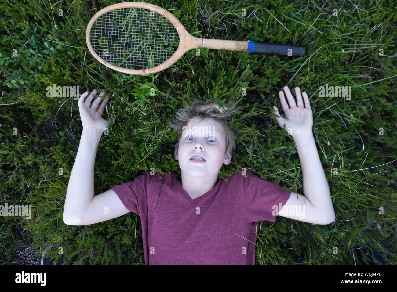 Ragazzo disteso sul campo con badminton racchetta Foto Stock
