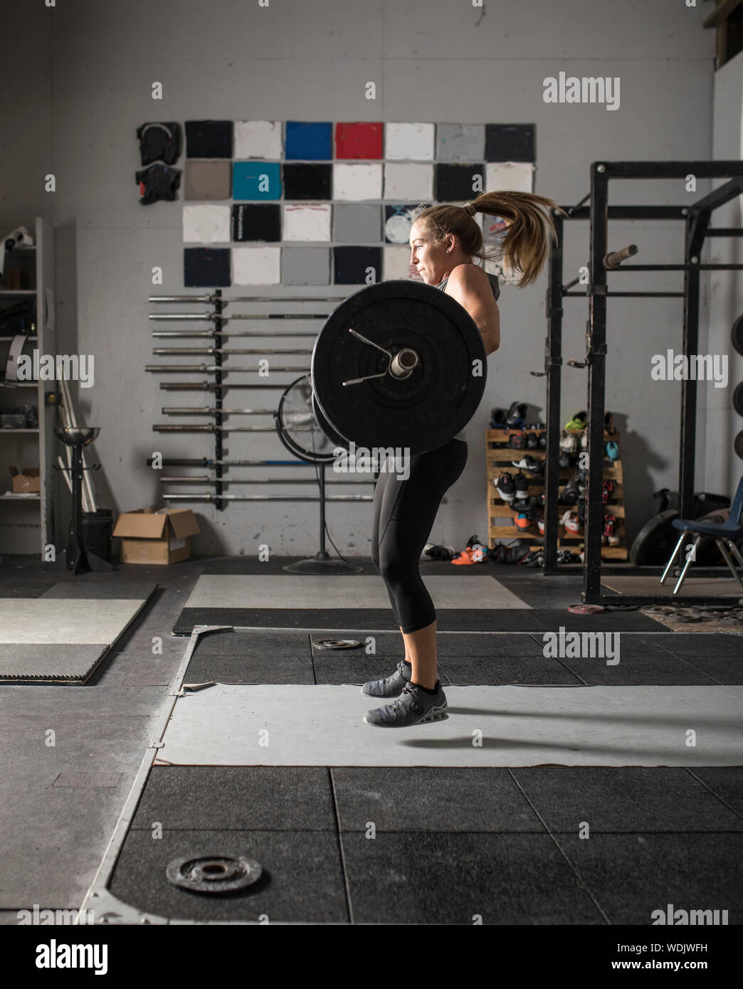 Azione girato di potere femminile lifter facendo pulire e jerk con pesi pesanti in palestra. Foto Stock