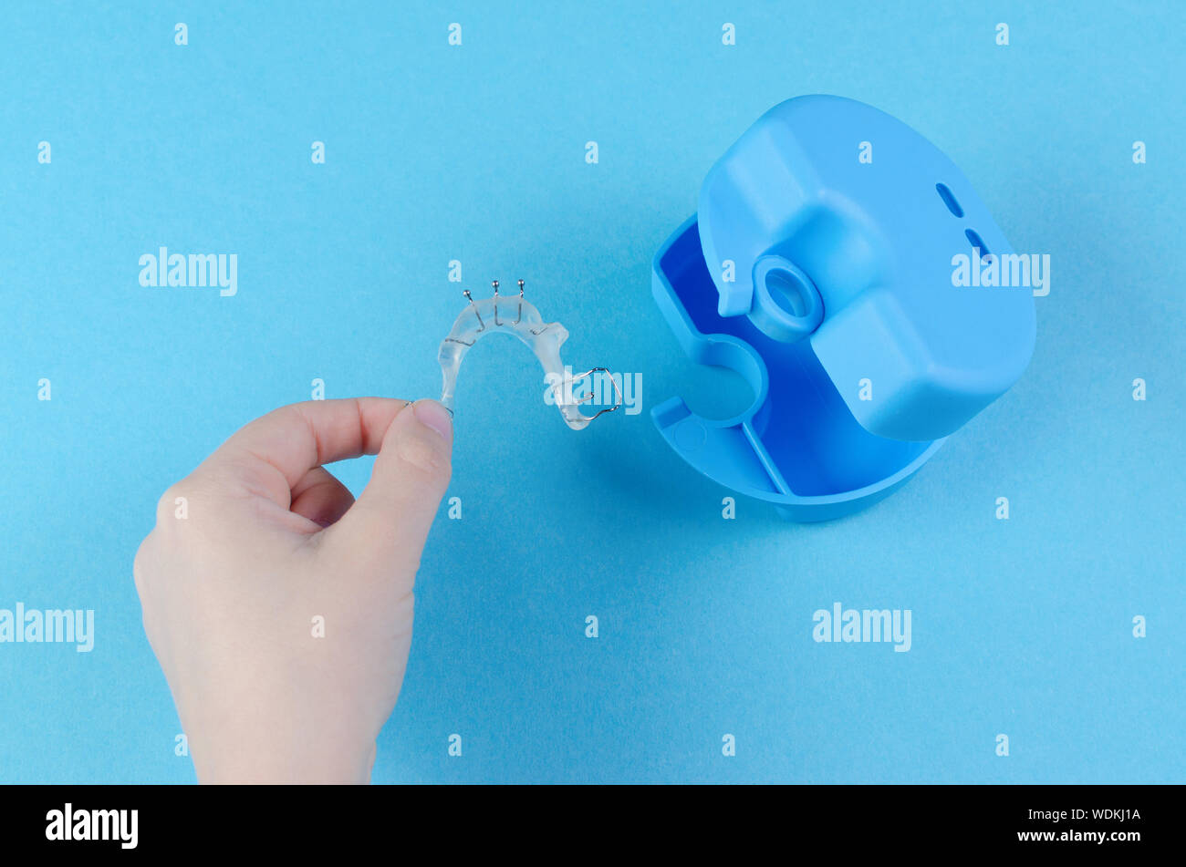 Bambino la mano con apparecchio ortodontico con box su sfondo blu Foto Stock