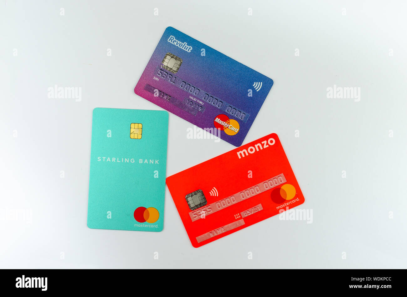 Starling, Monzo, Revolut carte bancarie poste una accanto all'altra. Concetto di concorrenza. Le informazioni sensibili è coperto con gli adesivi con cifre fittizia. Foto Stock