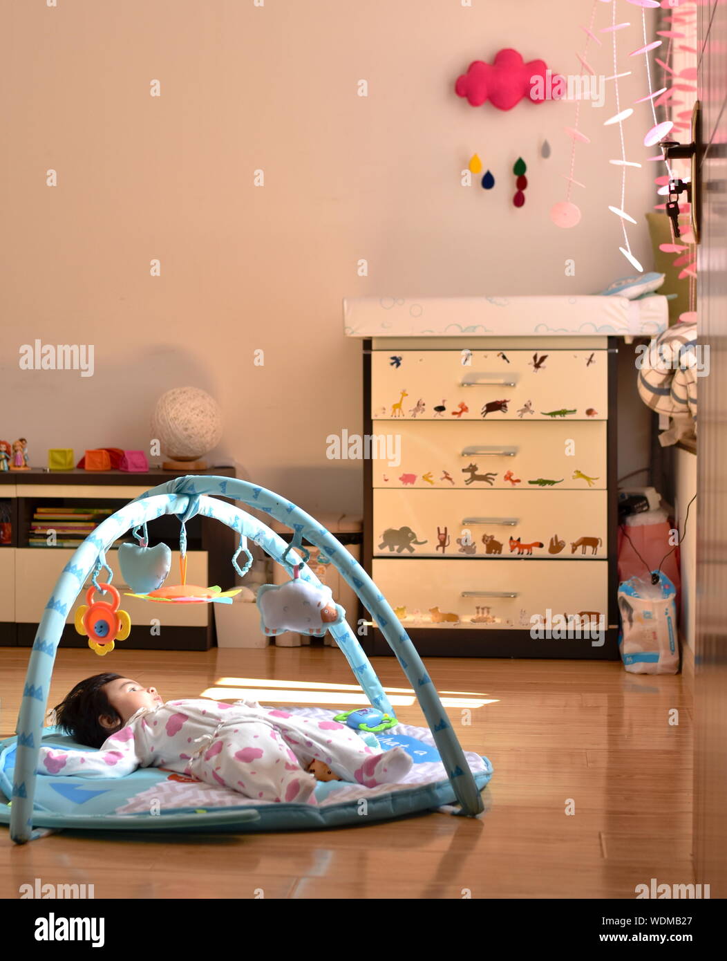 Baby girl nella nursery room sdraiato cercando in corrispondenza della finestra Foto Stock