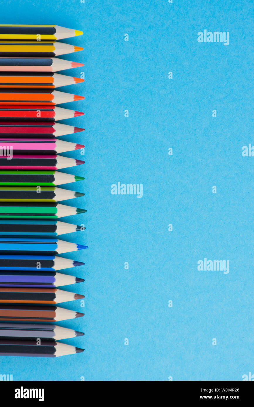 Foto verticale di una fila di matite colorate con diversi colori contro la  luce sfondo blu, matite sul lato sinistro con lo spazio di copia Foto stock  - Alamy