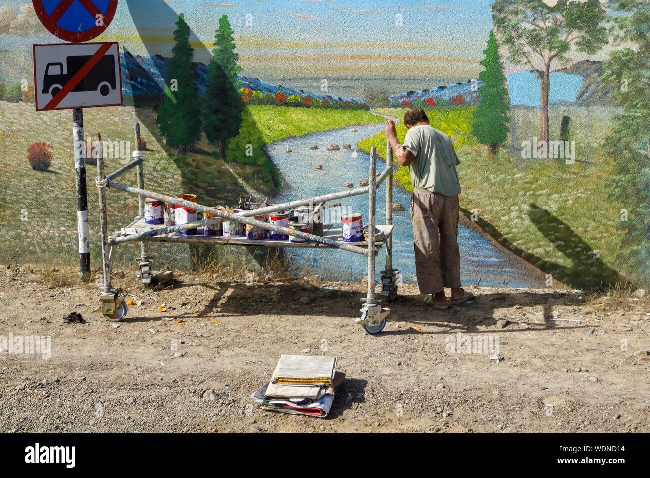 FUJAIRAH, UAE, 11 gennaio 2019: Street artista dipinge un bellissimo paesaggio su una recinzione Foto Stock