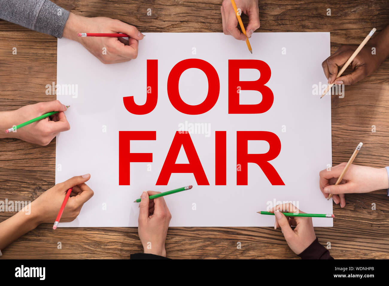 Una vista in elevato di imprenditori le mani la scrittura con matite colorate su Job Fair carta Foto Stock