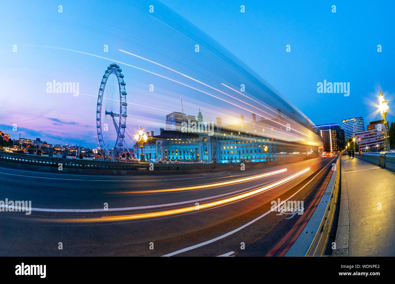 Paesaggio di Londra al blue ora, vista dal ponte di Westminster sull'occhio ruota e tracce di auto sulla strada, in Inghilterra, Regno Unito Foto Stock