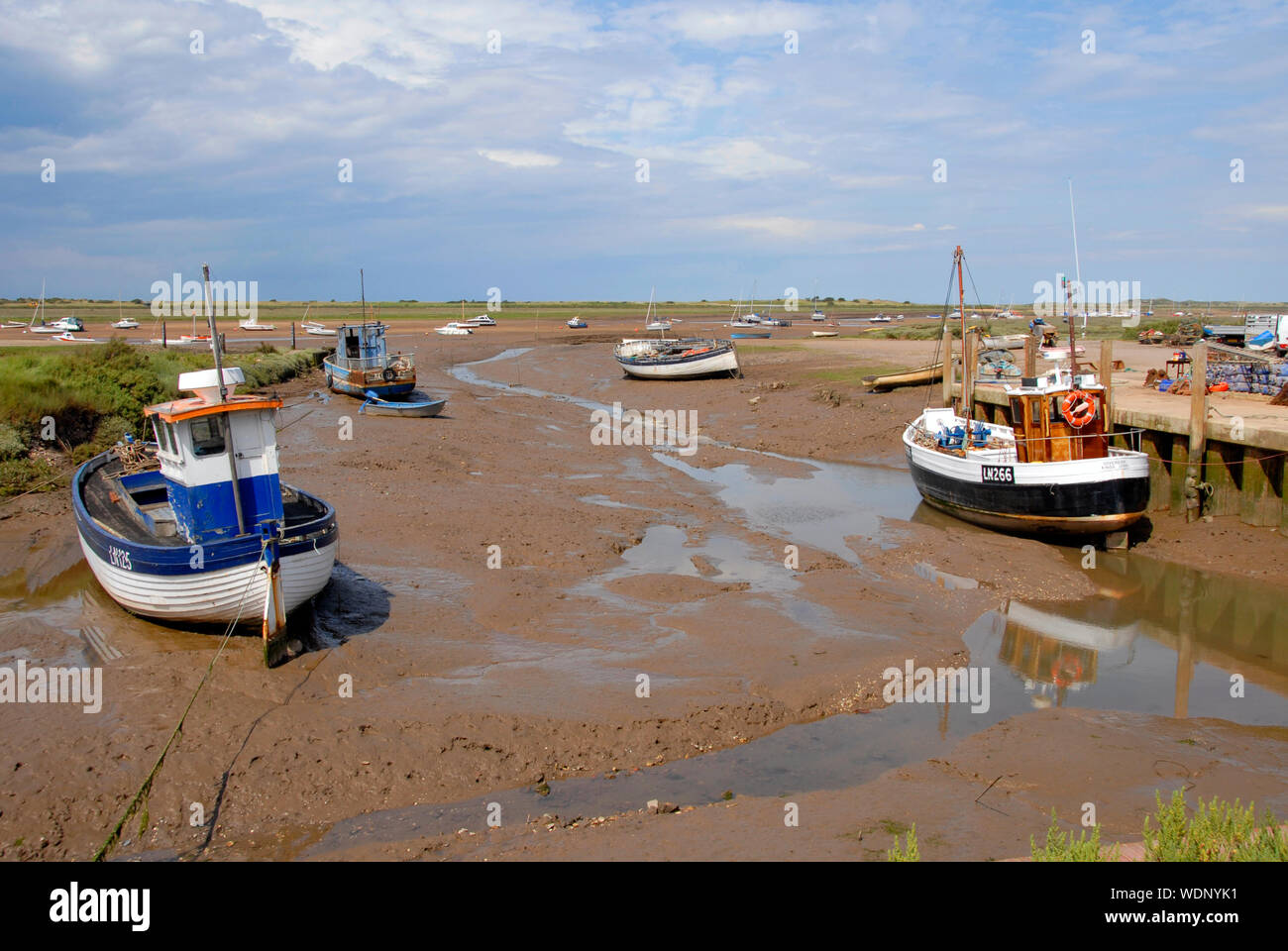 Barche sul fango con la bassa marea, Brancaster Staithe, Norfolk, Inghilterra Foto Stock