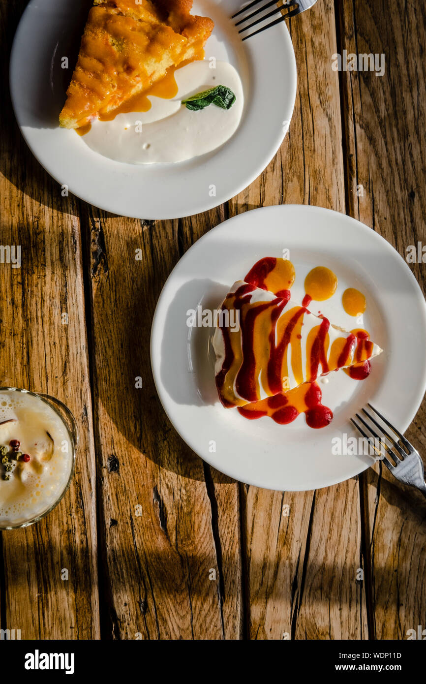 Due fette di caduta torte di zucca con panna e marmellata di salsa su tavola in legno rustico da sopra. Alimentare il concetto di fotografia. La luce diretta del sole Foto Stock