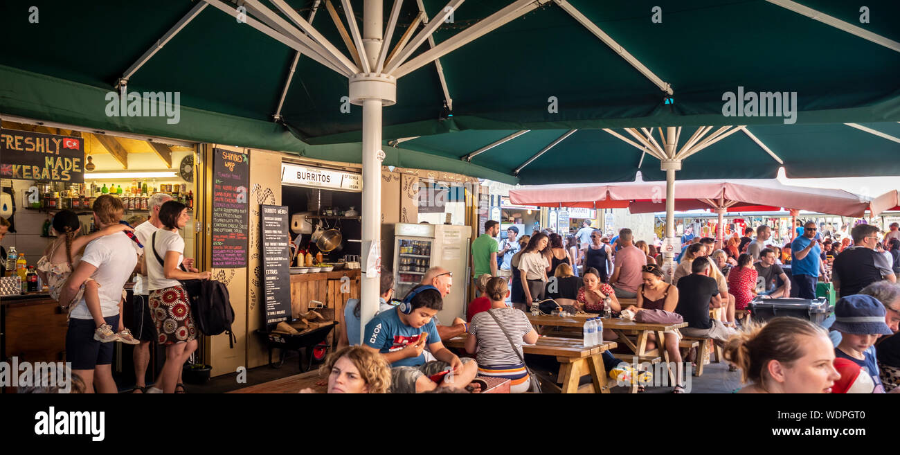 Area coperta con i commensali strada mangiando cibo al caos all'aperto del mercato food court, York, Regno Unito. Foto Stock