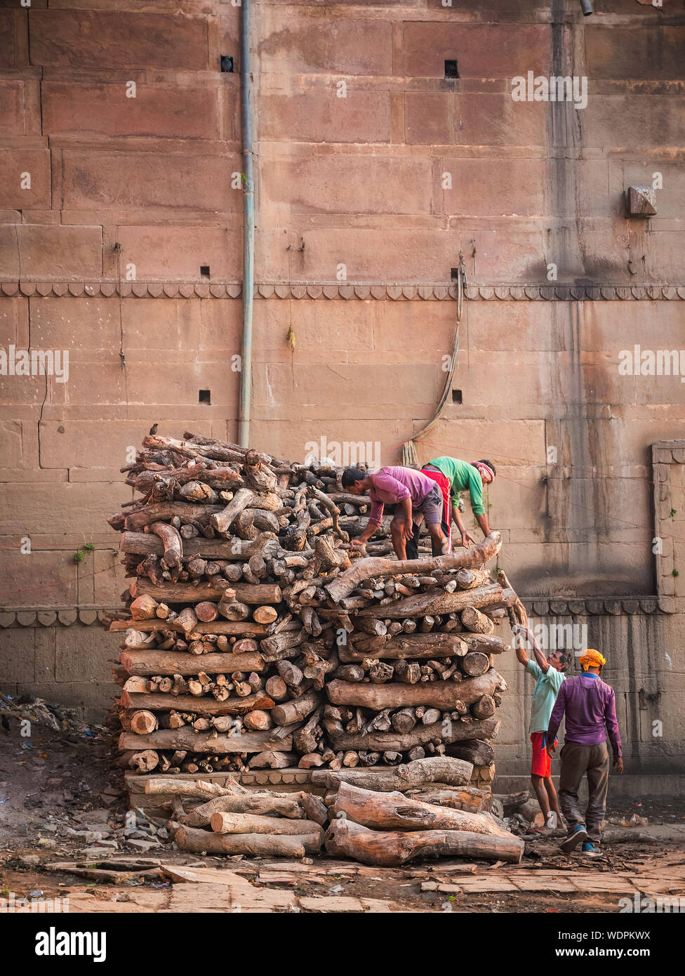 Indian uomini impilatura legno per roghi a Manikarnika (Combustione) Ghat di Varanasi, Uttar Pradesh, India, Asia Foto Stock