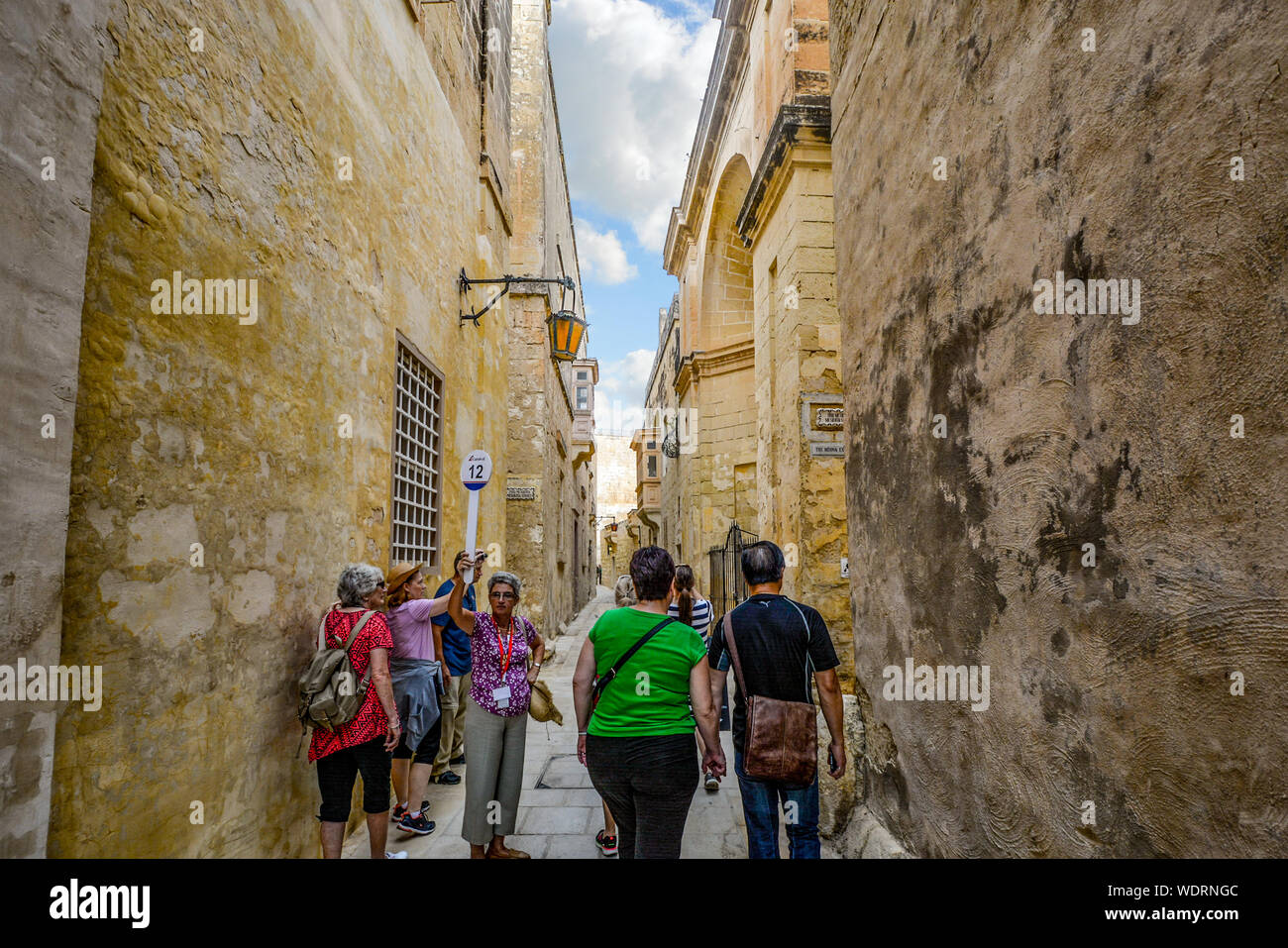Una guida turistica attende per il suo gruppo di tour per recuperare il ritardo accumulato nel corso di un tour a piedi della medioevale città fortificata di Mdina, Malta Foto Stock