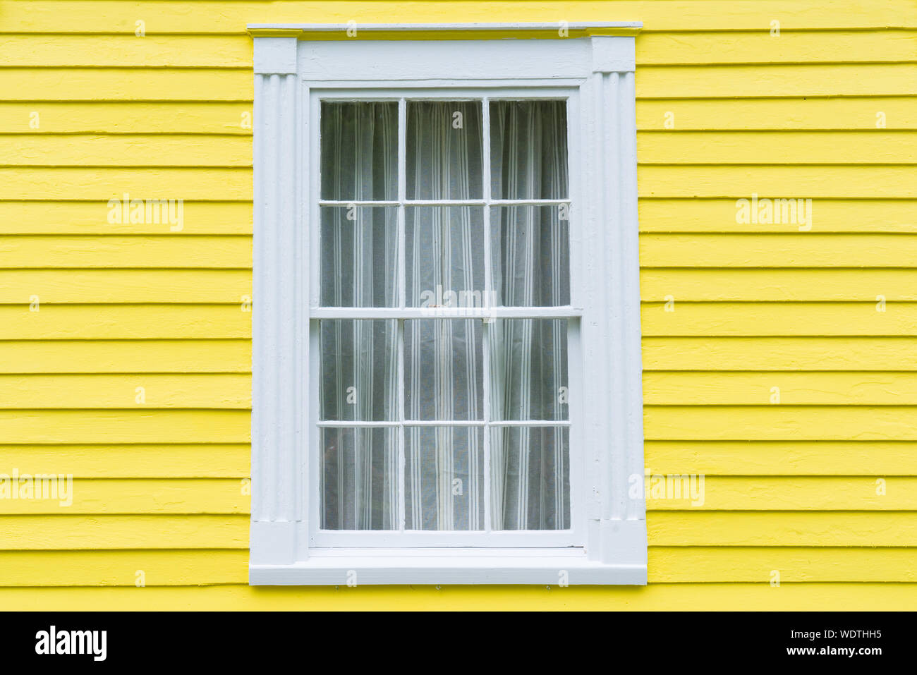 Il vecchio telaio in legno finestra con colore giallo brillante clapboard schierata Foto Stock