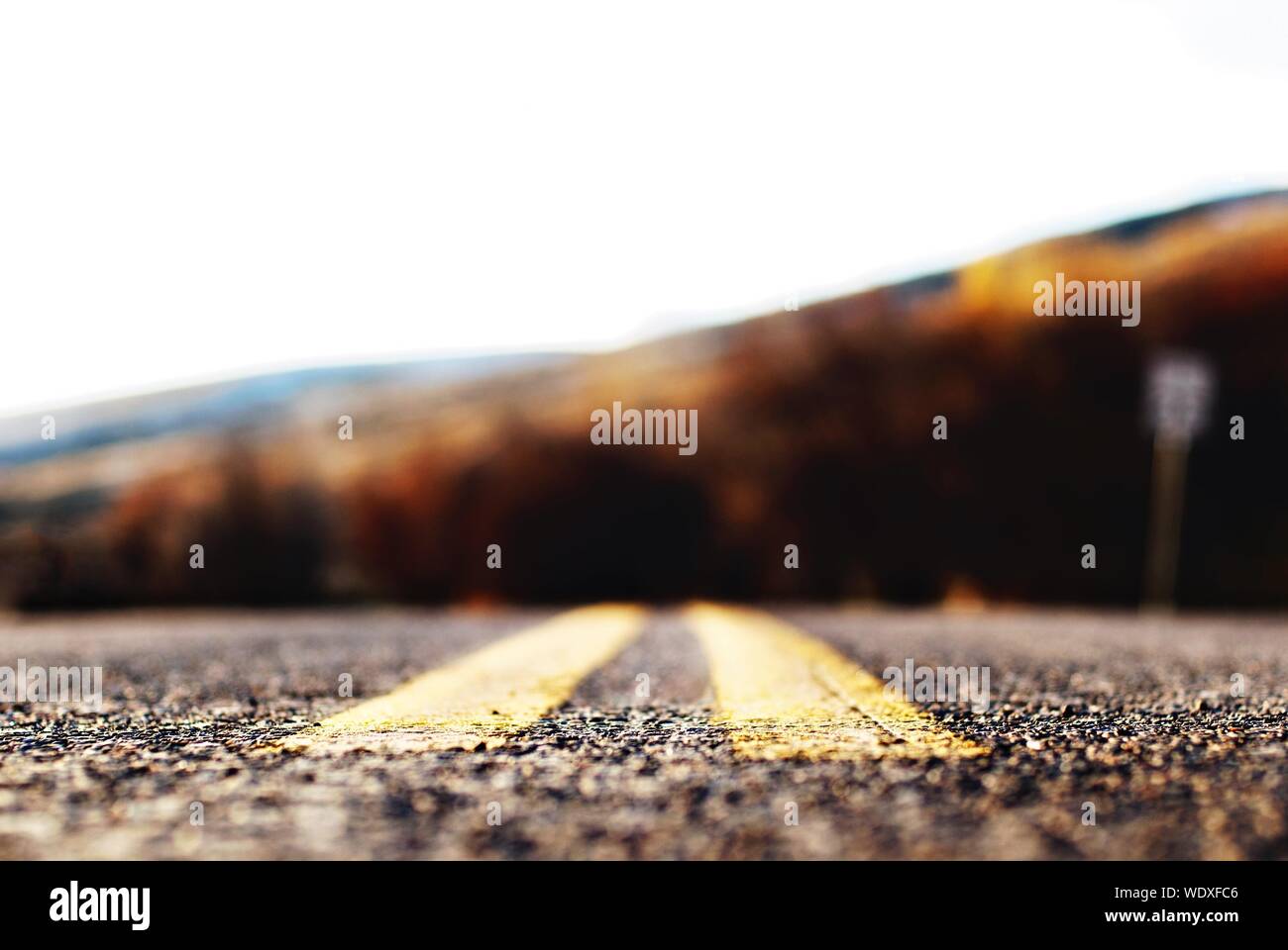 Close-up della doppia linea gialla sulla strada di montagna contro Sky Foto Stock