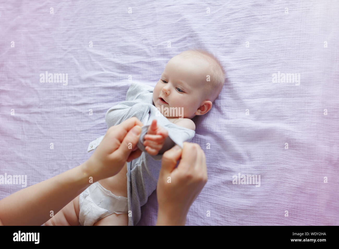 Infermiera genitore cambiando pannolino per neonato Figlia Figlio bambino. Babysitter genitore prendersi cura del bambino e mettendo su abiti onesie. La vita autentica Foto Stock