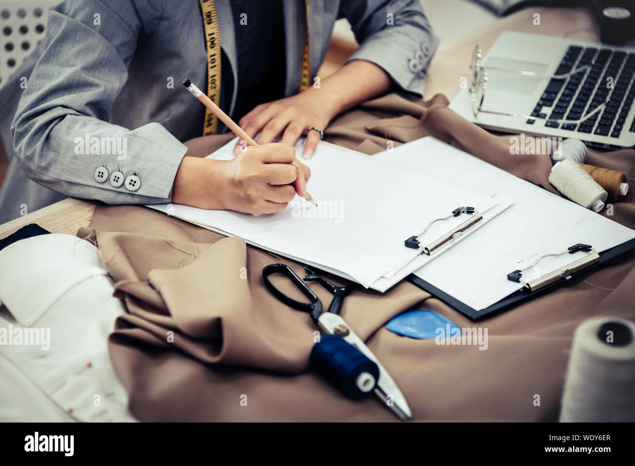 Primo piano della femmina attraente designer di moda mano lavorando in ufficio a casa officina. Elegante fashionista donna creazione di panno nuovo design collection. Ta Foto Stock