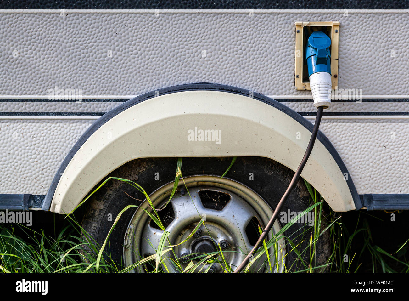 Close-up di un serbatoio per gas con inserito un pistola per alimentare carburante ad una vecchia auto sulla strada, contro uno sfondo di erba verde. Esterno della vettura con Foto Stock