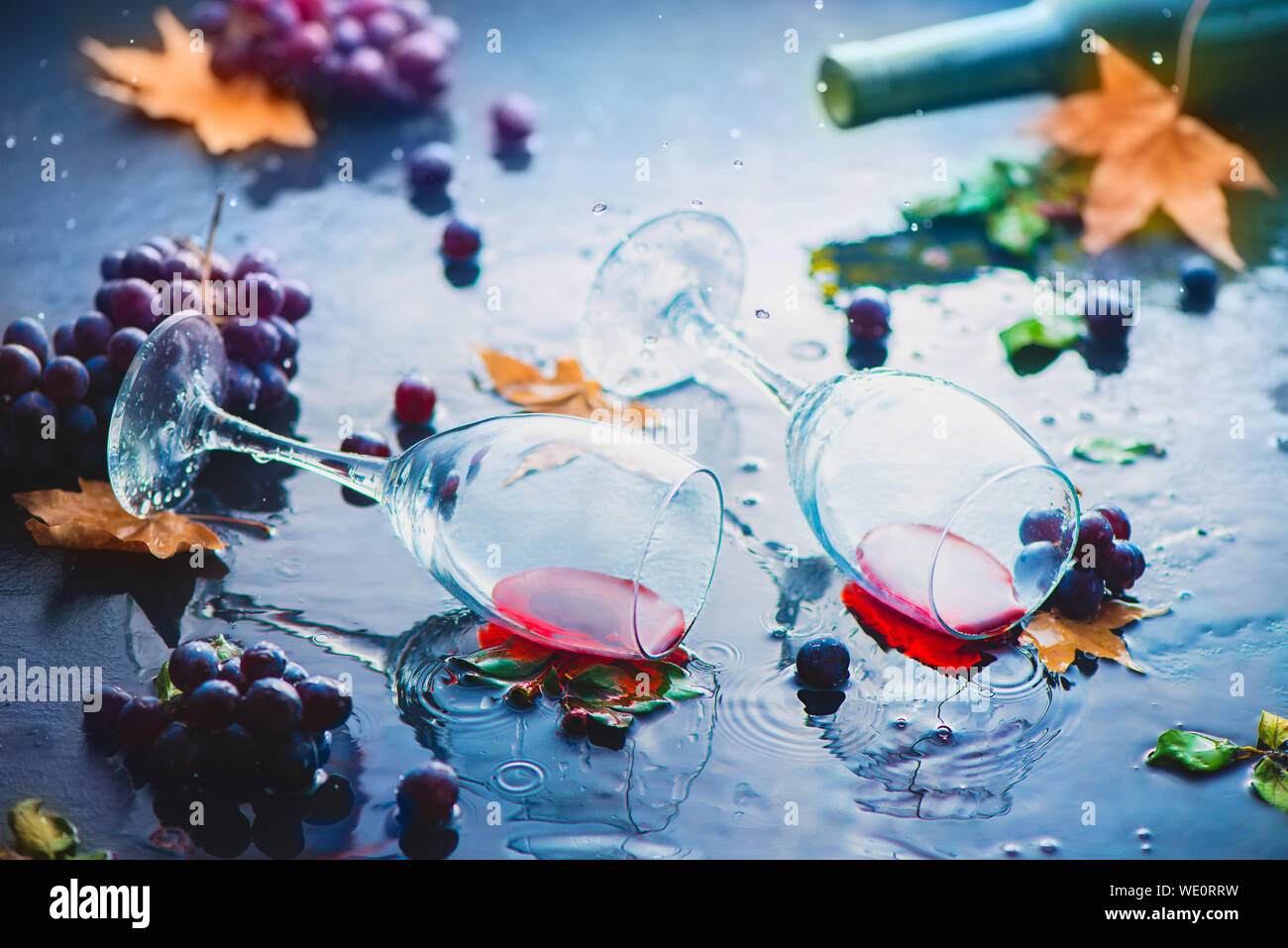 Bicchieri a calice da vino con uve e caduta foglie sotto la pioggia. Creative autunno bere la fotografia con spazio di copia Foto Stock