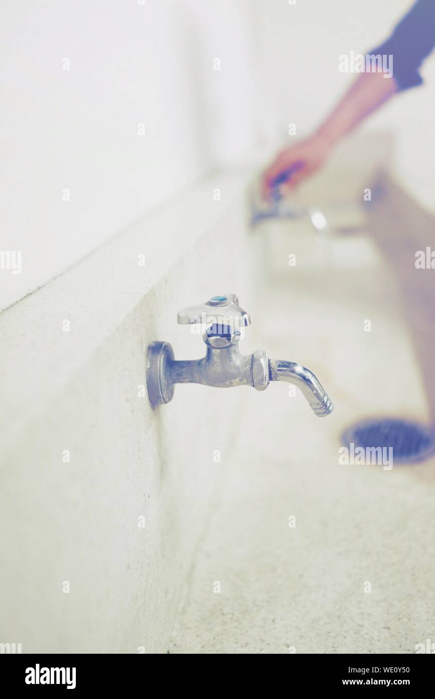 Ritagliate la mano di uomo con rubinetto in Toilette pubblica Foto Stock